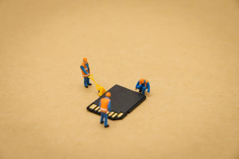 Miniature people Construction worker repair with Storage card or memory card using as background Technology concept and maintenance concept with copy space for your text or design.