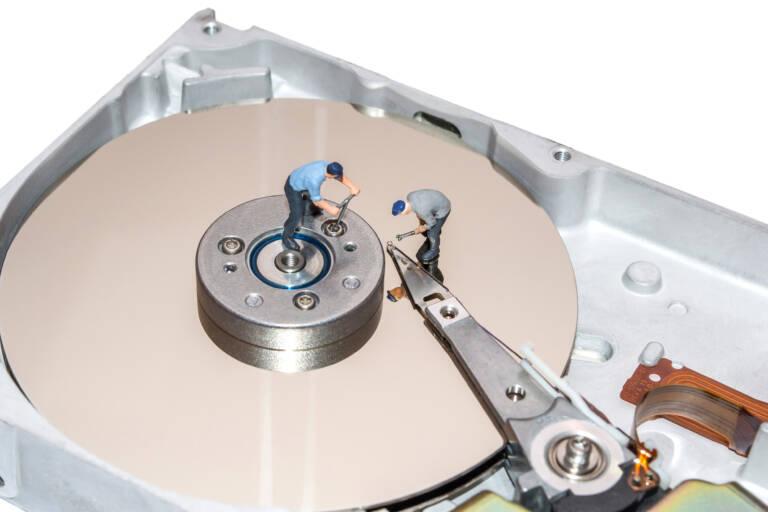 Miniature people repairing the hard drive. A broken computer equipment. Figures of people. The team of employees.