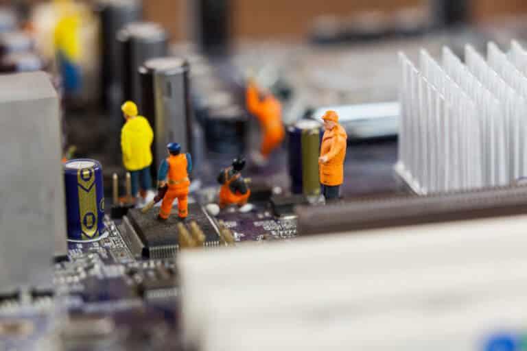 Conceptual image of miniature workers working on chip of motherboard